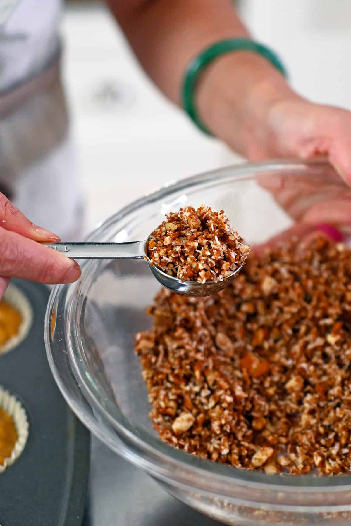 A tablespoon is used to scoop up the paleo streusel topping for the apple muffins.
