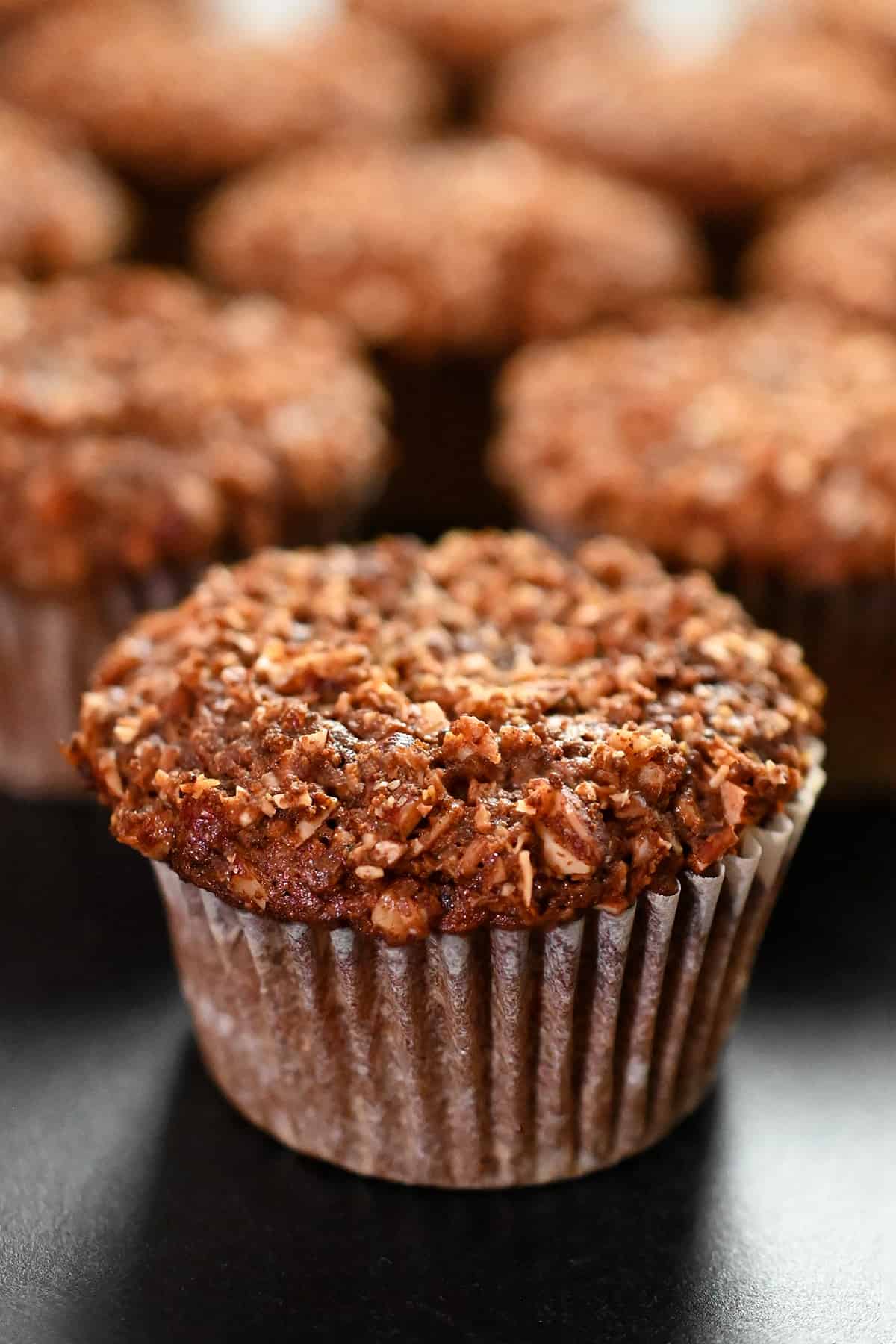 A closeup side view of paleo and gluten free apple muffins on a black background.