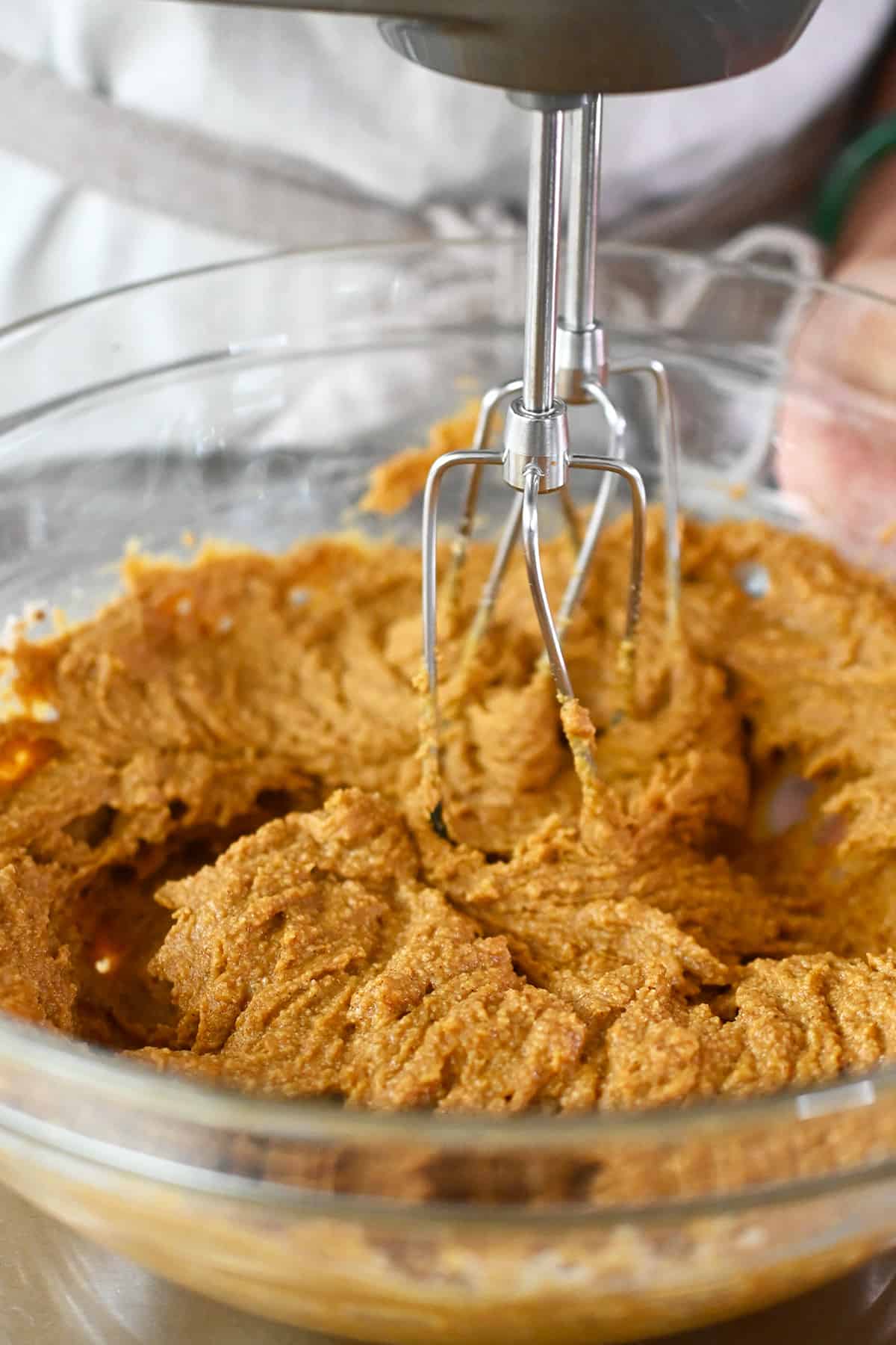 A closeup photo showing a hand mixer blending the batter to make paleo pumpkin cookies.