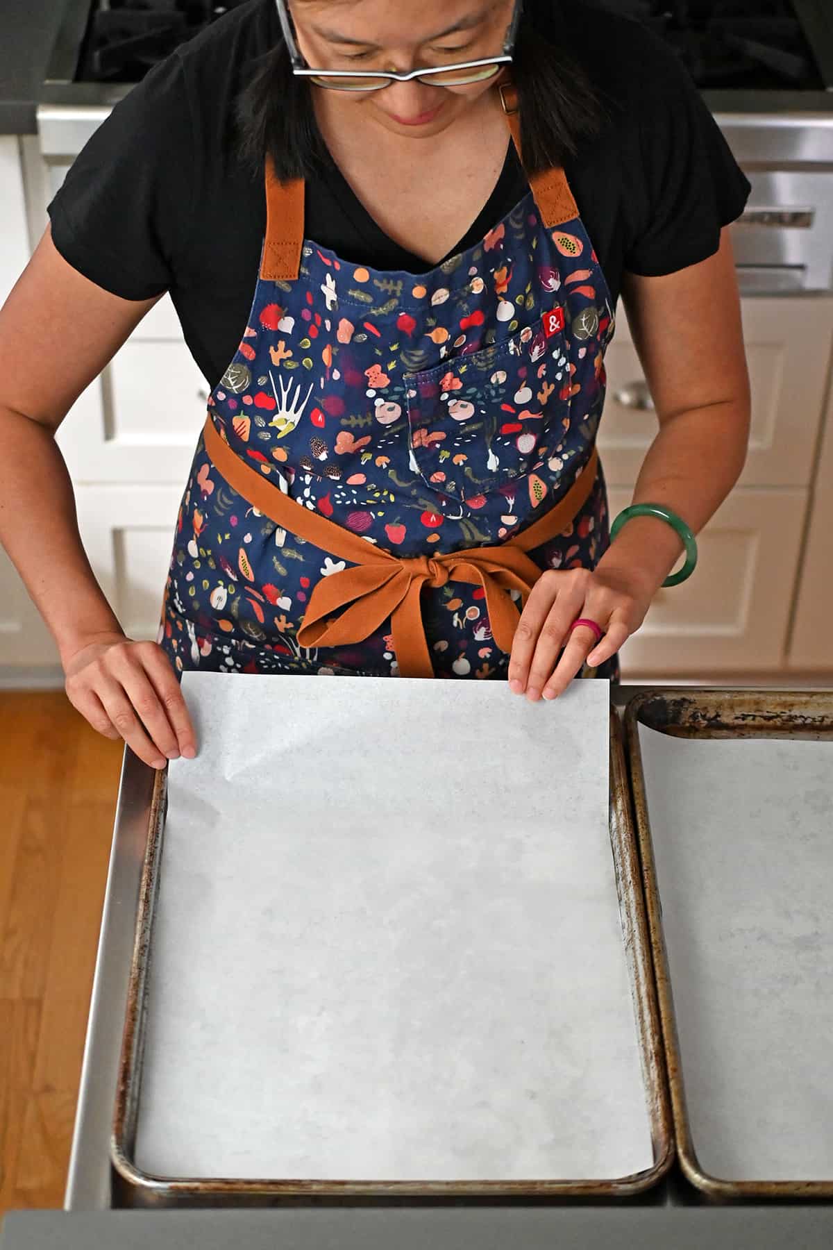 Lining two rimmed baking pans with parchment paper.