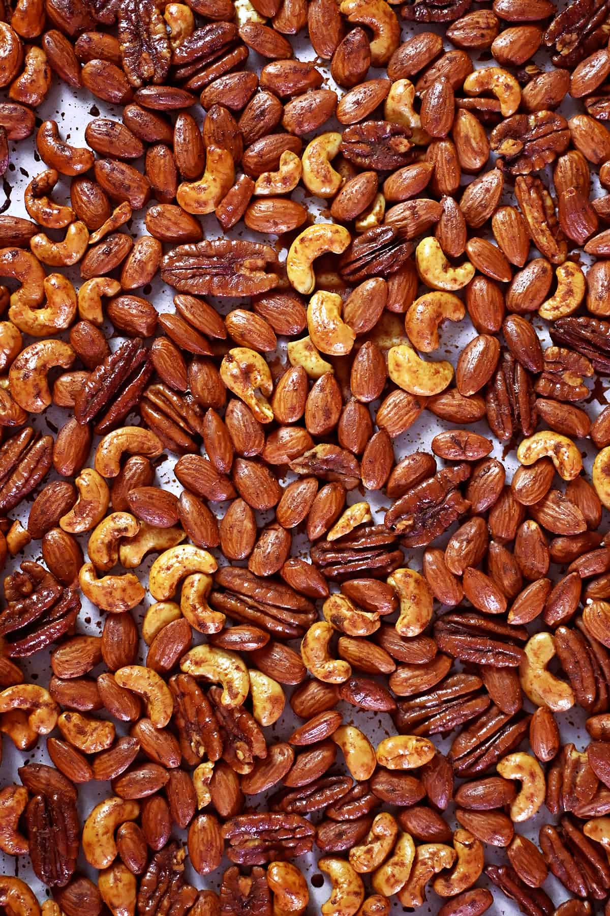 An overhead shot of a rimmed baking sheet filled with freshly roasted paleo spiced nuts.
