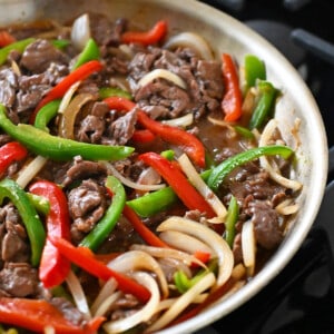 A side view of a skillet filled with cooked paleo and gluten free pepper steak.