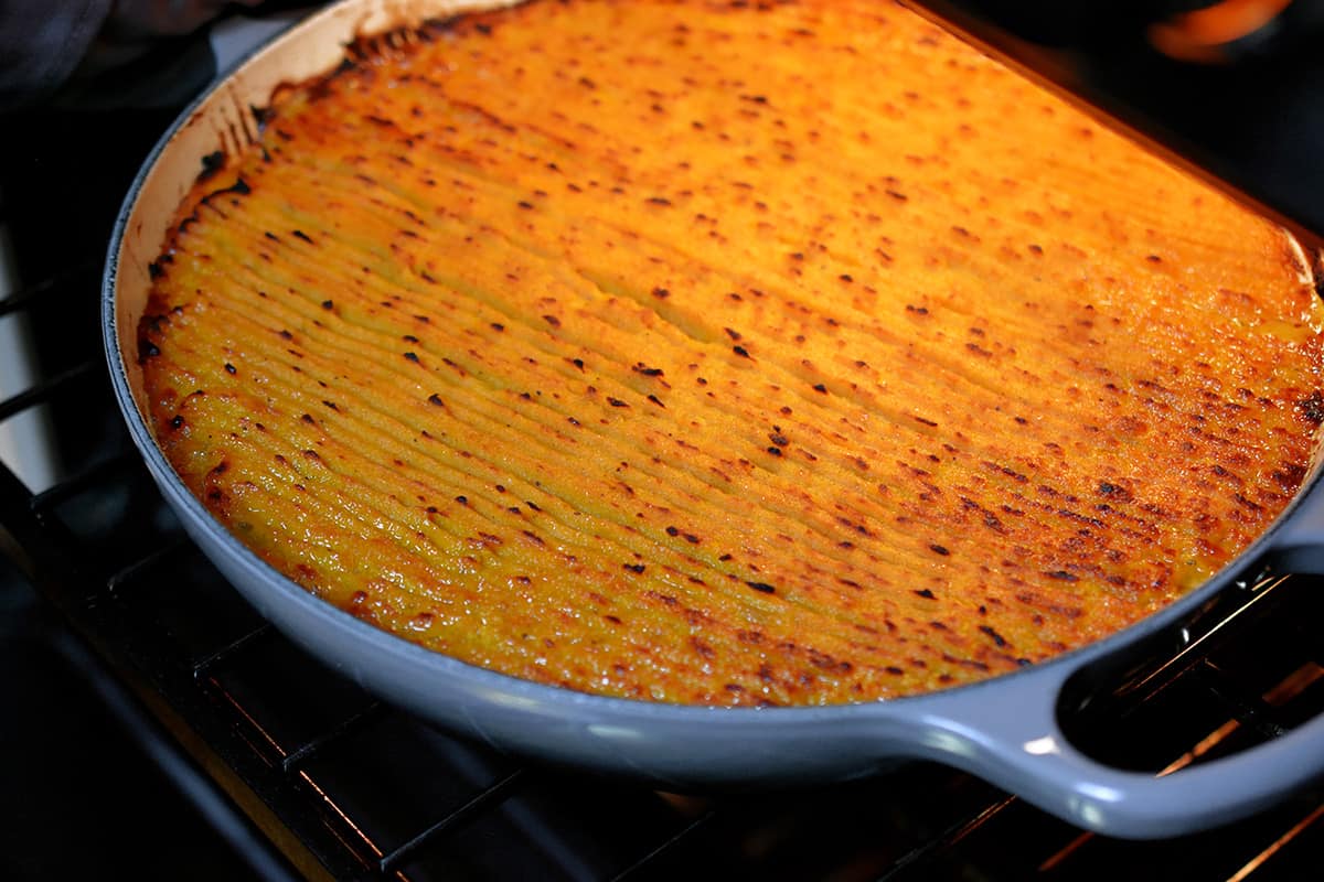 An Indian-spiced shepherd's pie in a round enamel cast iron skillet under the broiler.