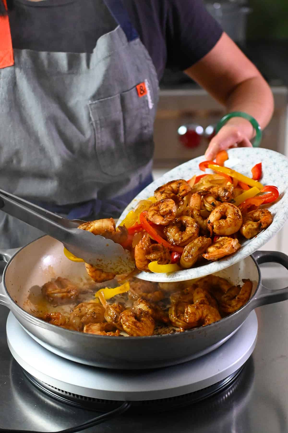 Adding the cooked fajita vegetables and shrimp back into the skillet.