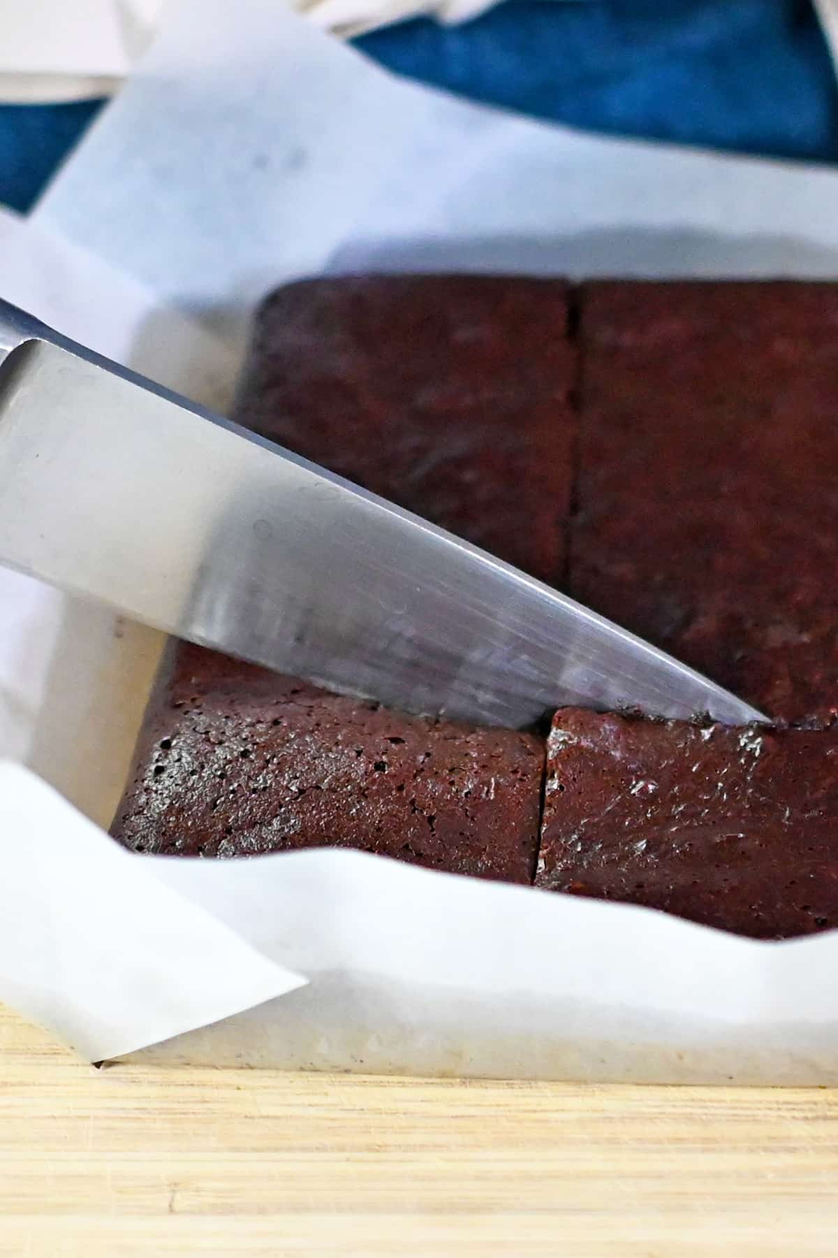 A chef's knife is cutting paleo brownies into squares.