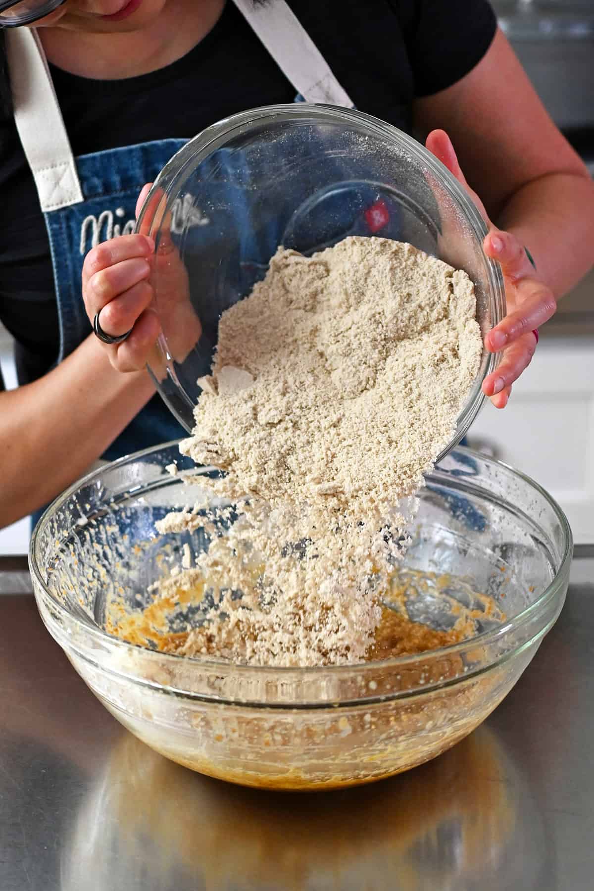 Add the bowl of dry ingredients to the glass bowl of wet ingredients to make the paleo banana cookies.