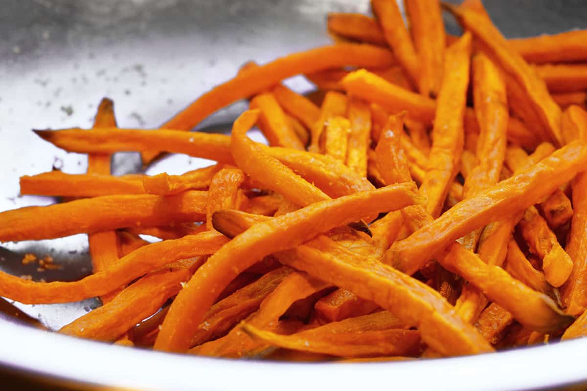 A silver bowl filled with crispy oven fried sweet potato fries.