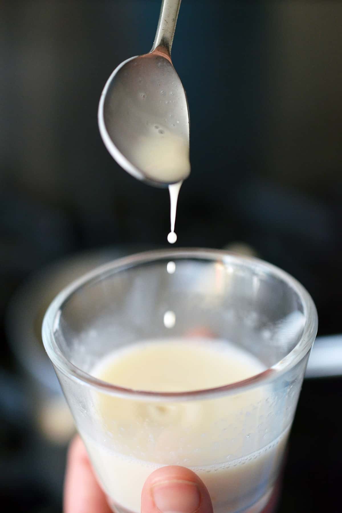 Transferring warmed almond milk into a glass jar with gelatin.