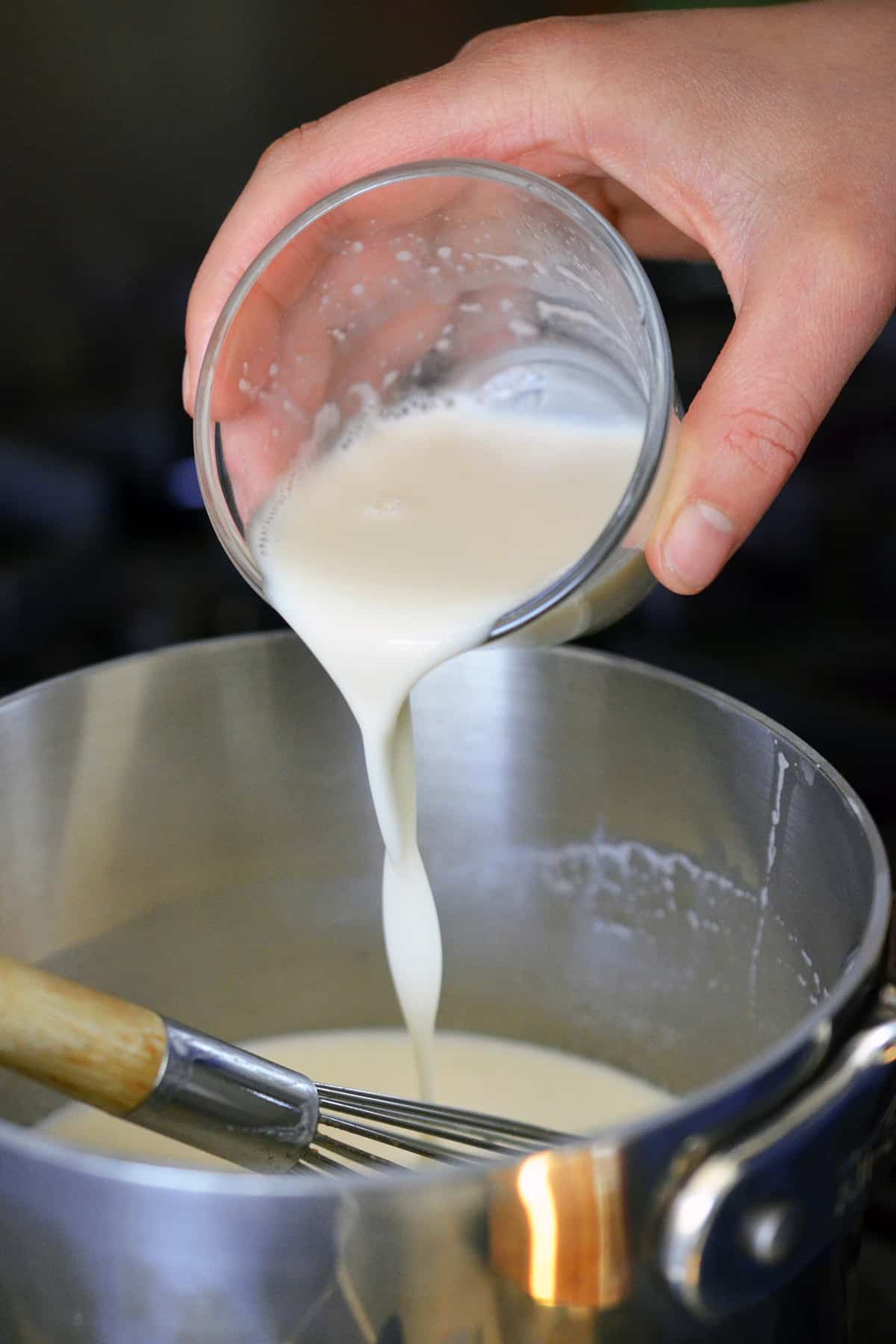Pouring some diluted gelatin into a saucepan to make Panna Cotta.
