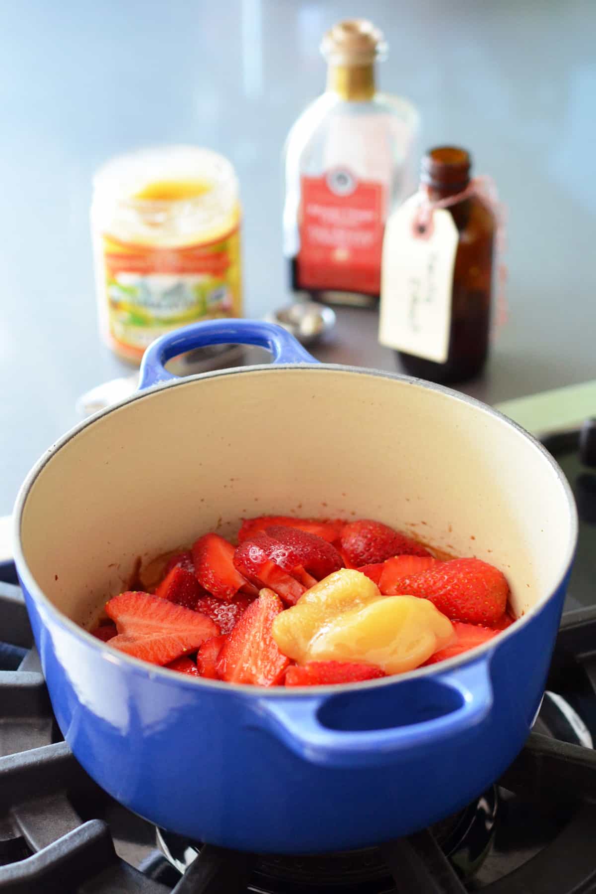 A blue saucepan filled with the ingredients to make strawberry balsamic compote.