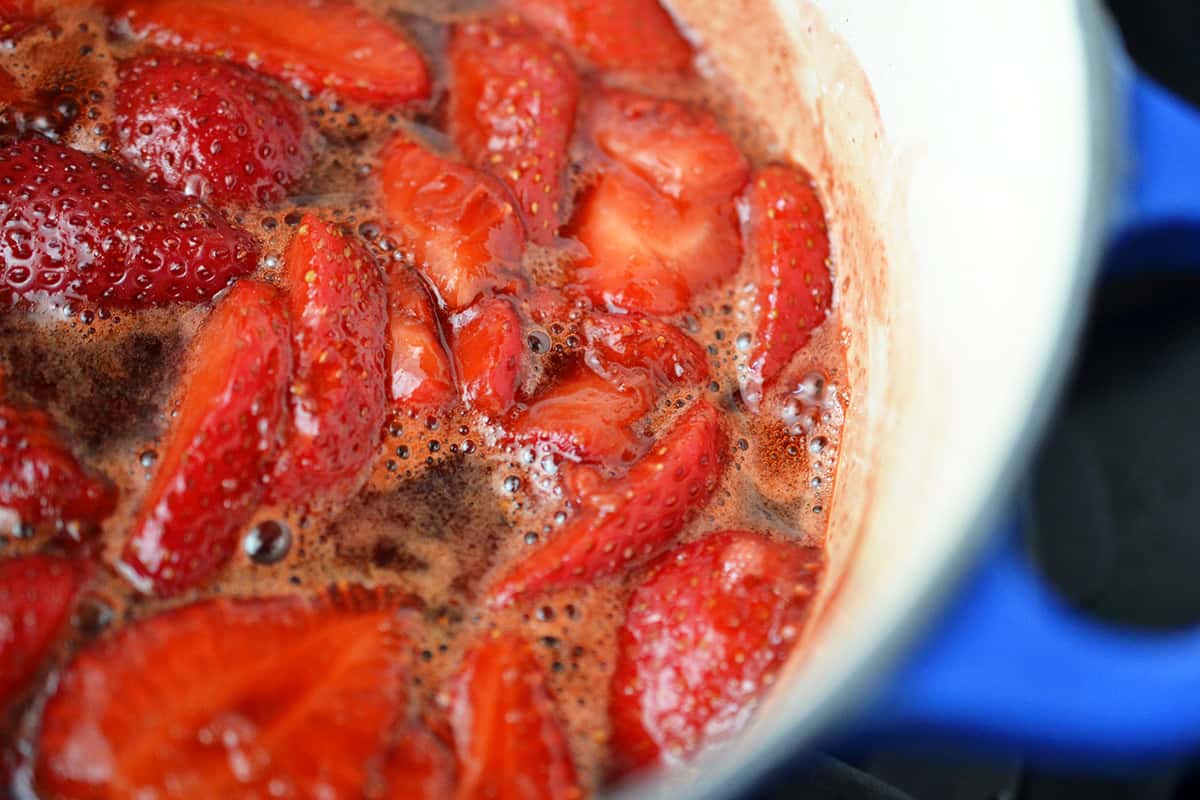 A closeup shot of the strawberry sauce simmering in a small saucepan.