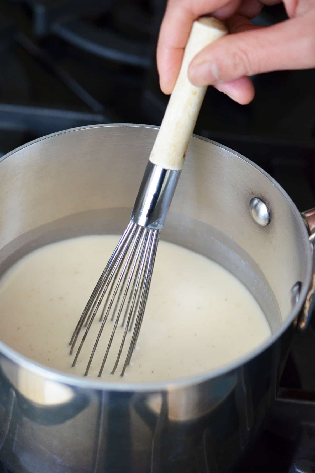 Whisking the Panna Cotta mixture in a small saucepan as it warms up.