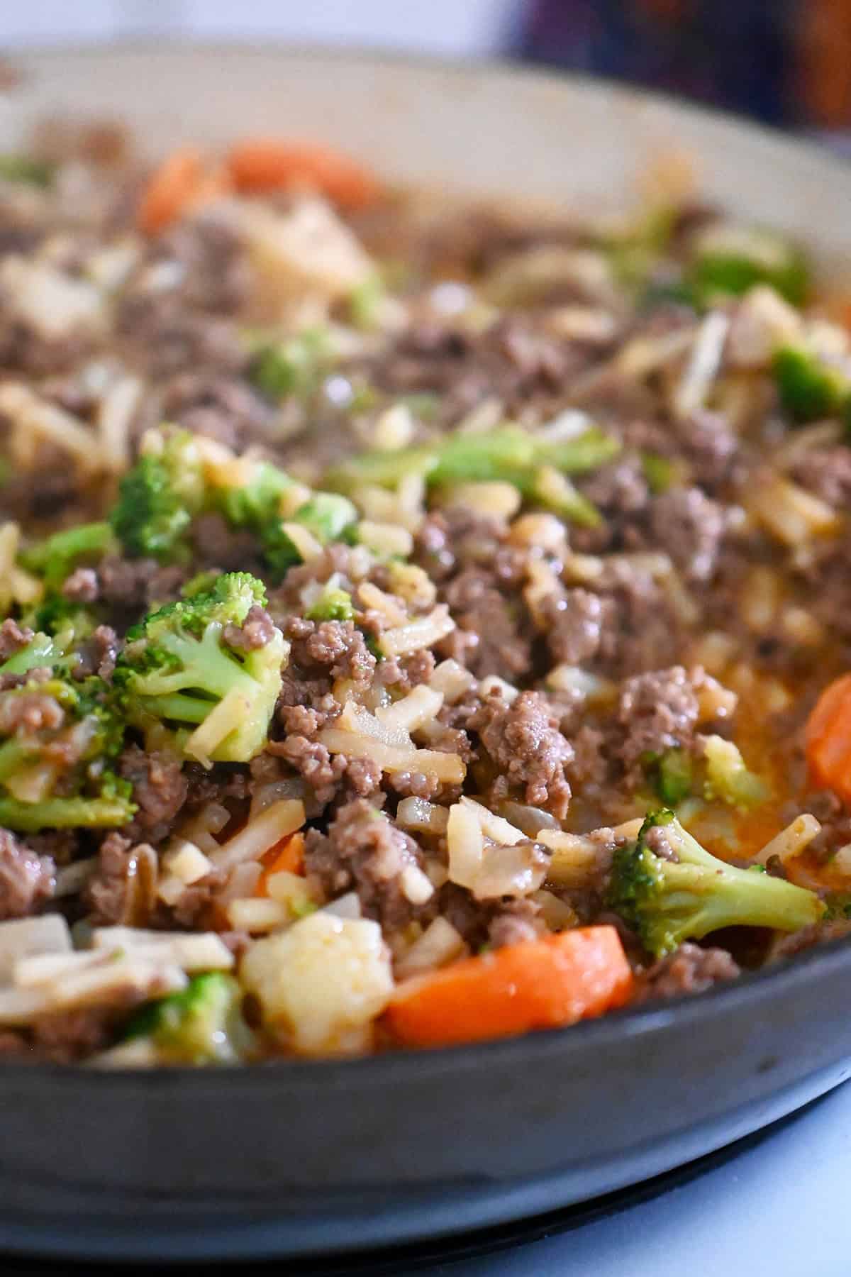 A closeup of the ground beef, shredded potatoes, and mixed vegetables after it has finished cooking.
