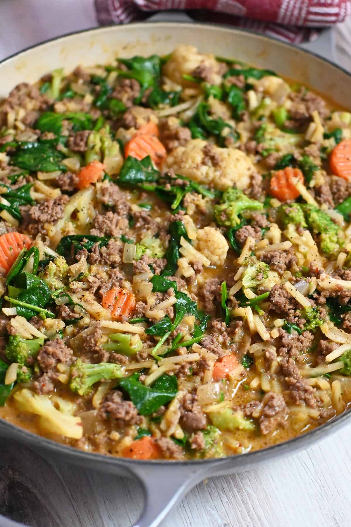 A closeup look of a skillet filled with ground beef, shredded potatoes, and mixed veggies in a savory, gluten-free and dairy-free sauce.
